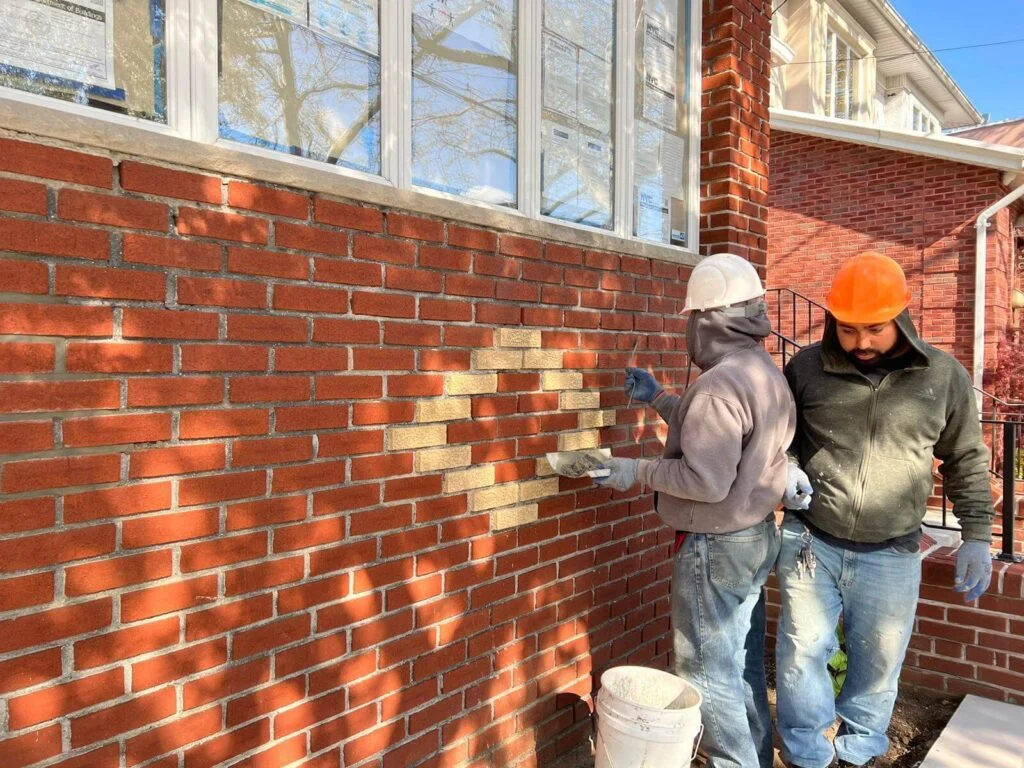 Technician restoring damaged brick and stone facade on a New York brownstone building