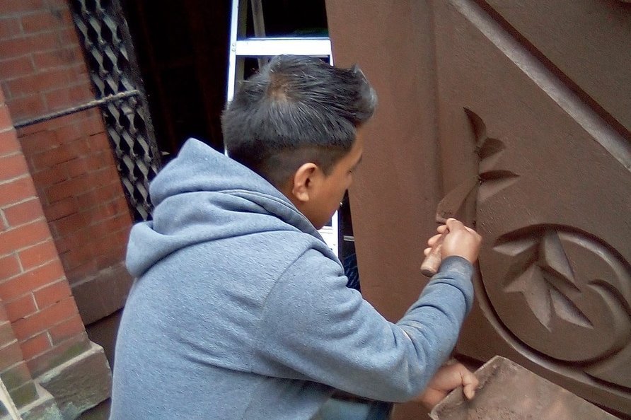 Mason restoring carved stone detail on a NYC brownstone facade
